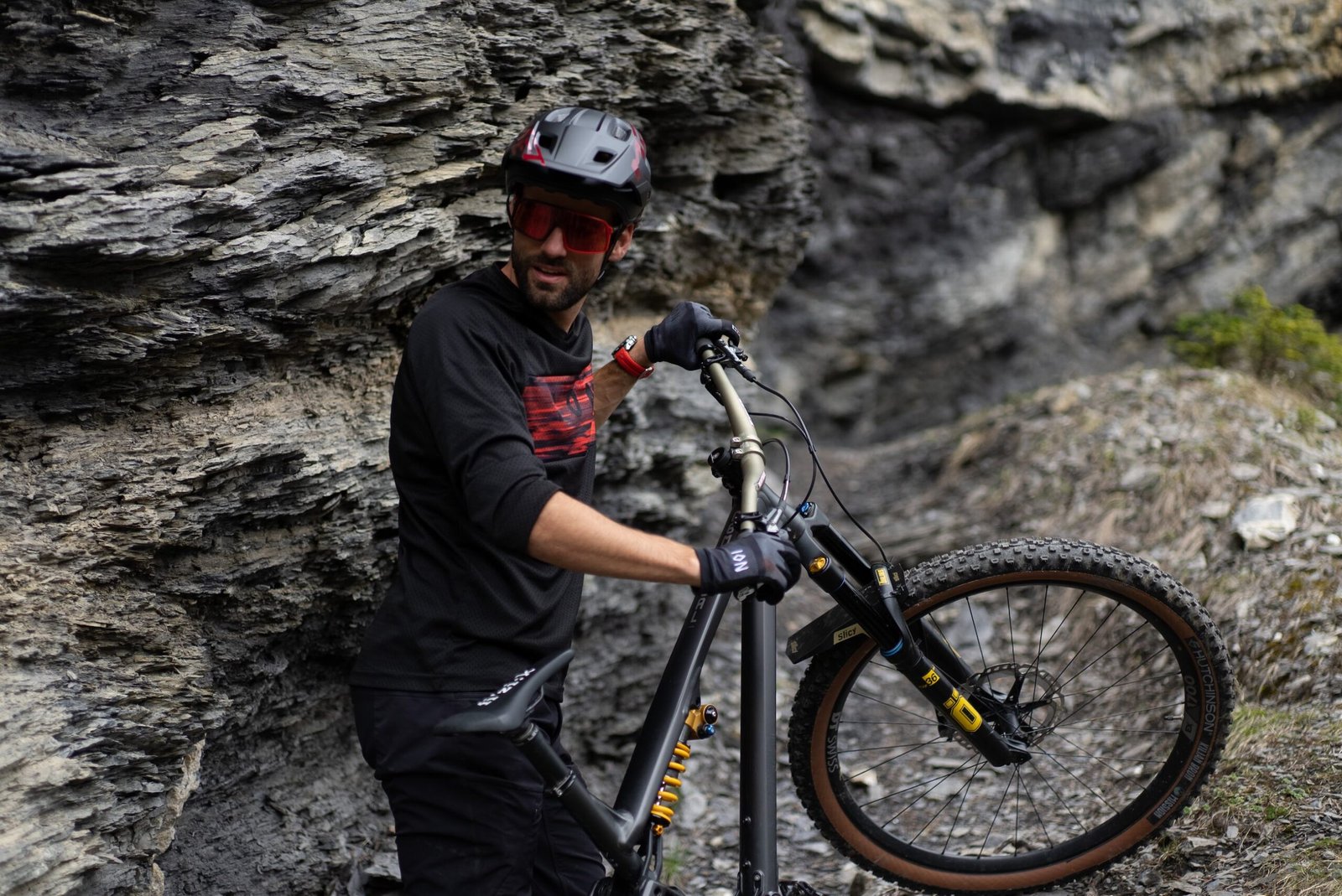 Kilian Bron en tenue VTT avec son vélo équipé d’accessoires Slicy, lors d’une session freeride sur terrain rocheux.